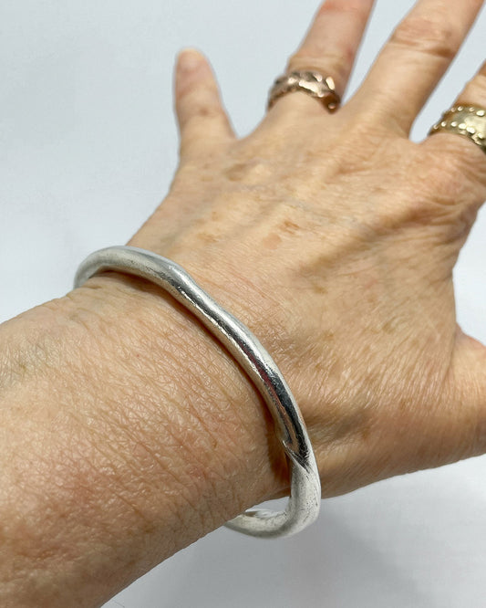 A single heavy organic fine silver bangle being shown on a wrist