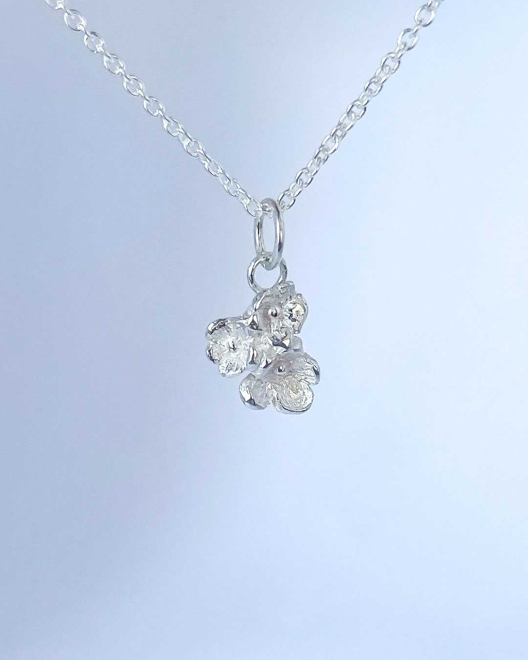 A close up of the Dainty Flower Bouquet of three sterling silver flowers hanging from a Sterling Silver Chain