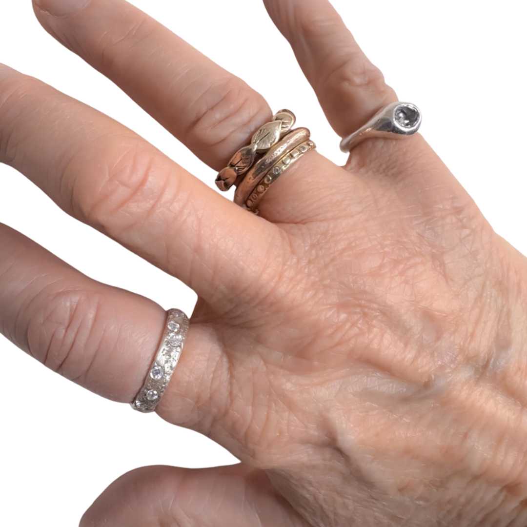 Sterling silver sandcast ring with flush-set cubic zirconias, worn on a hand against a white background — showcasing the ring’s subtle sparkle and textured, sculptural form.
