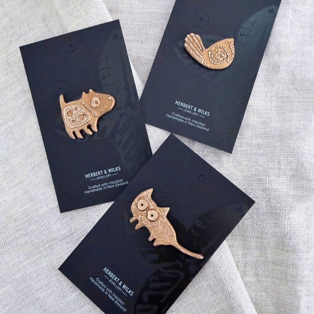 Bronze Cat, Dog and Pīwakawaka Pins on Herbert & Wilks jewellery cards