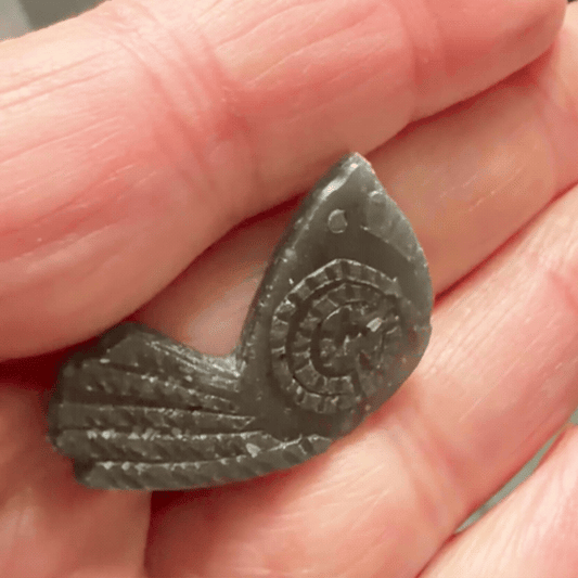Wax bird pin model held in the hand, showing the raised lines and textures created from the original collage.