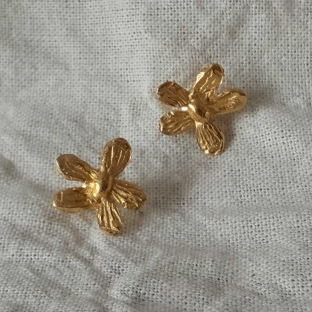 A pair of Flora 18ct Gold Plate flower stud earrings sitting on a linen cloth, handmade botanical jewellery