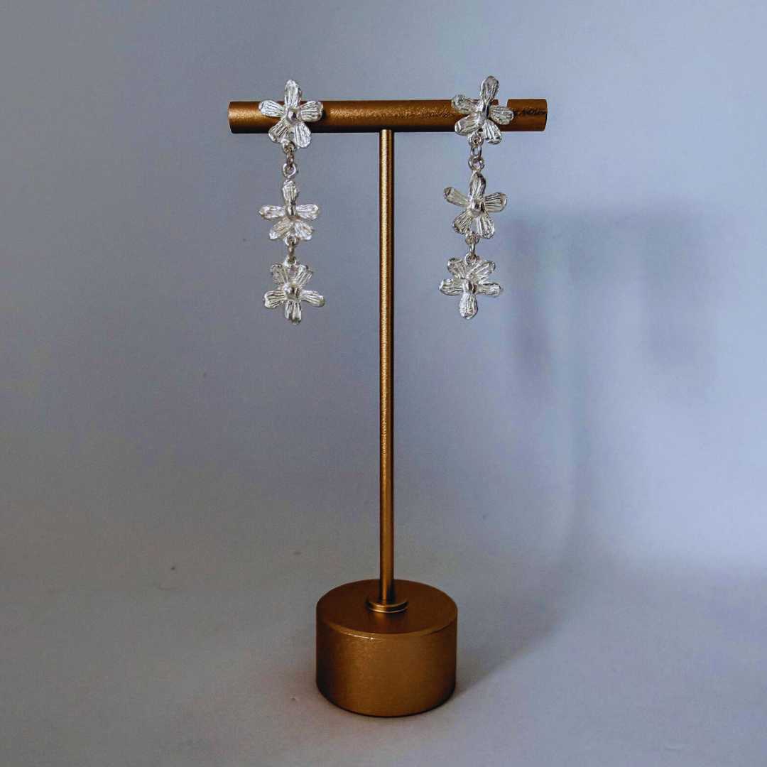 Flora Trailing Flower Earrings displayed on copper earring stand with shadow showing three-dimensional botanical flower design - 45mm sterling silver drop earrings handmade in New Zealand