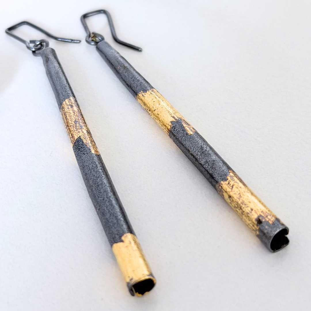 Close-up of Keum-Boo pendant earrings showing hand-applied gold on textured sterling silver and elongated sculptural form.