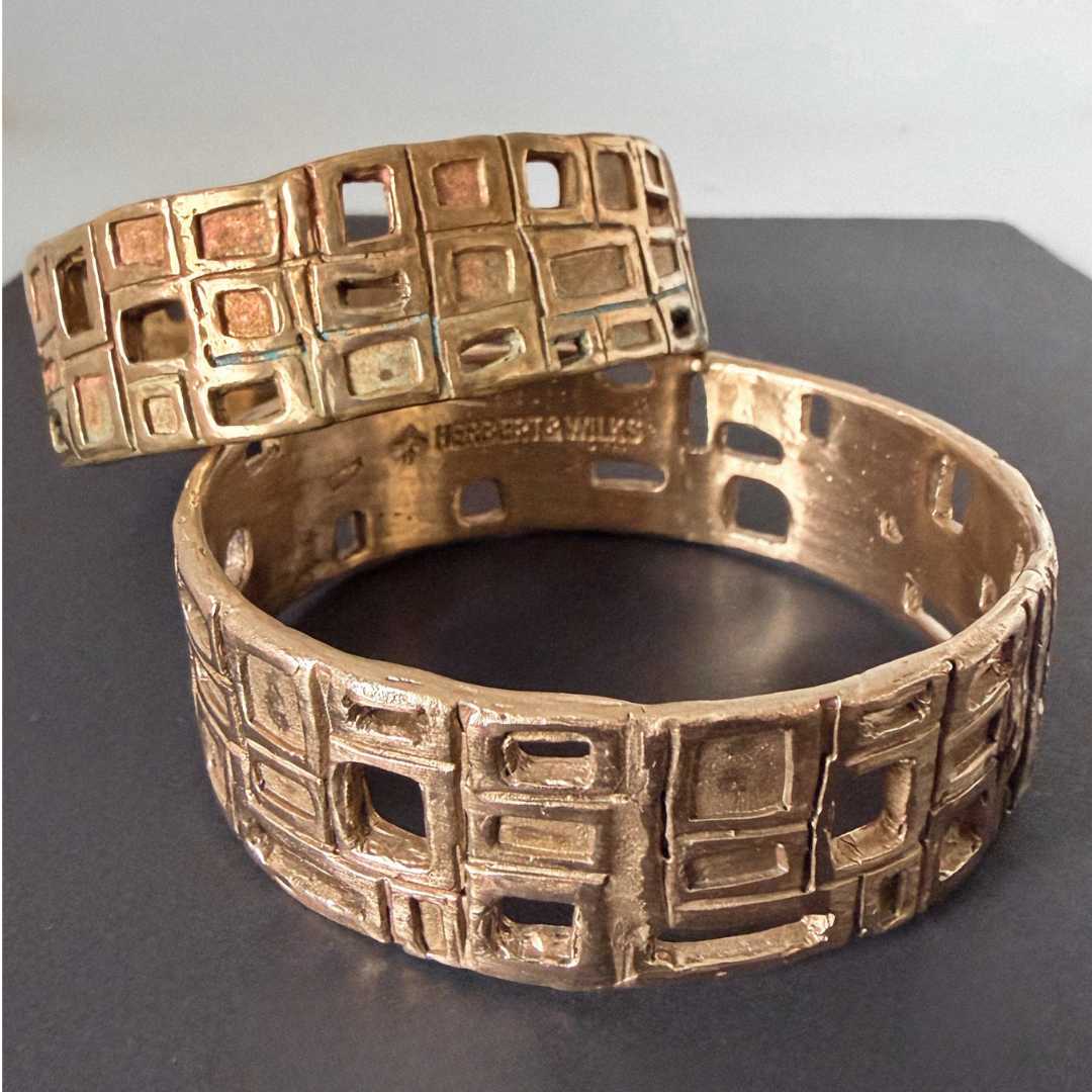 Two HerbertandWilks Modernist Bangles in warm, caramel-toned bronze, showing the unique green and pink patina developing on the cast texture of the back bangle.
