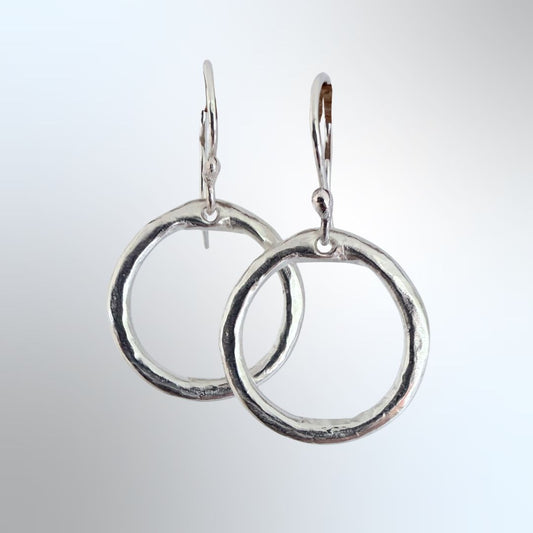 Organic Circle Hoop Earrings in sterling silver hanging, clean product shot against light grey-blue background — HerbertandWilks