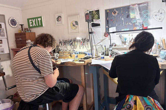 Two participants learning jewellery making at the benches during a lost wax carving workshop in Auckland.