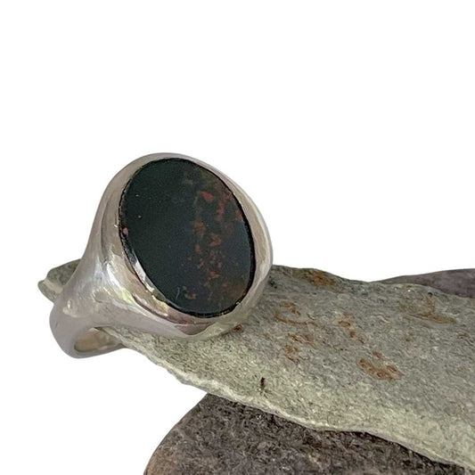 Handcrafted silver Bloodstone Signet Ring resting on a rock with white background – HerbertandWilks Jewellery