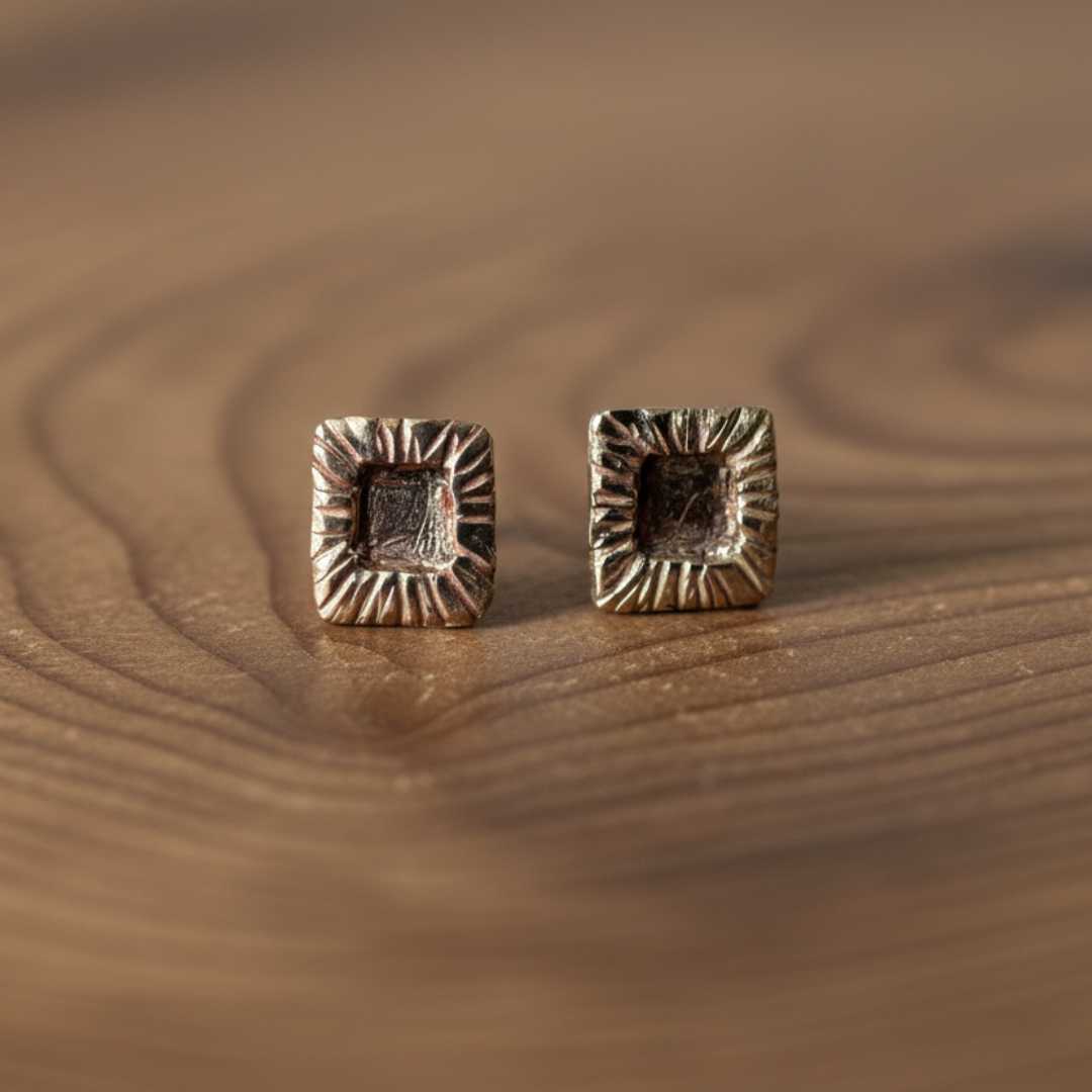 Pair of bronze strata rectangle stud earrings on natural wooden surface showing handcrafted texture