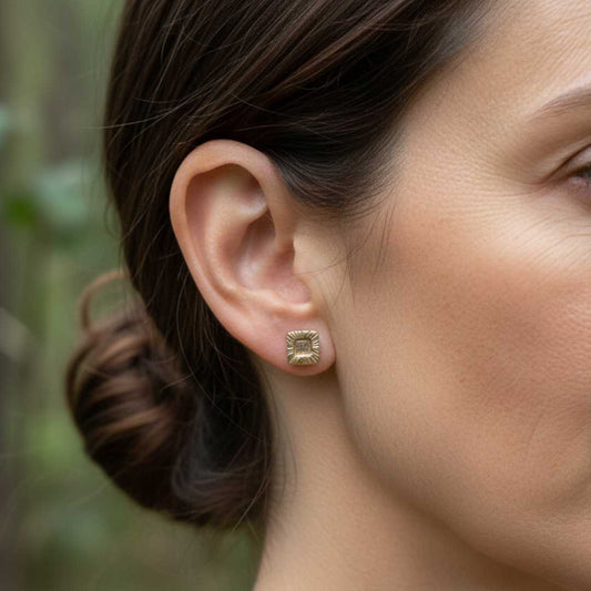 Woman wearing small bronze strata rectangle stud earrings 8mm showing delicate scale in natural outdoor setting