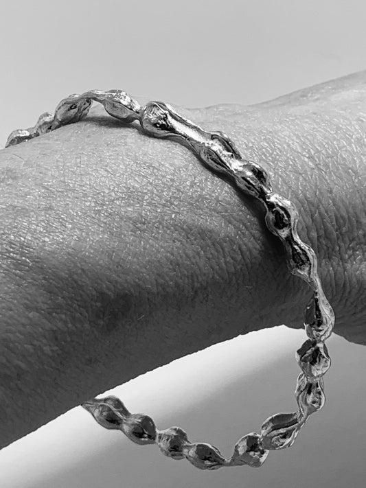 Black and white photo of the Kōwhai Pod Sterling Silver Bangle being worn, highlighting its curved form and how it sits naturally on the wrist.