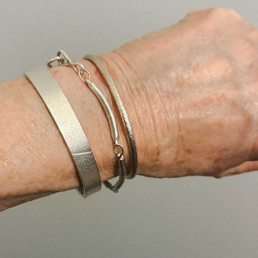 Maker Cuff worn on wrist with other Herbert & Wilks jewellery pieces, showing how the sterling silver cuff layers beautifully for everyday wear