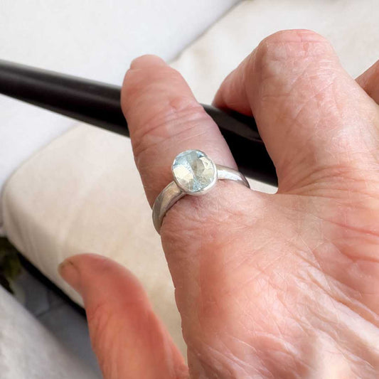 Manatū Ring worn on the hand, viewed from a slightly elevated front angle showing the oval aquamarine and sterling silver bezel.