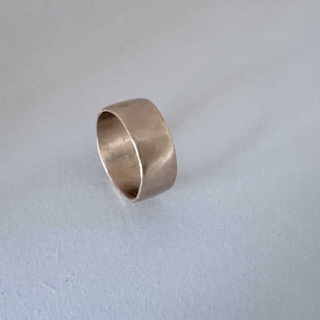 Wide band organic ring in 9ct yellow gold standing upright at angle, showing interior comfort fit and tapered organic band profile from 8.5mm to 7mm