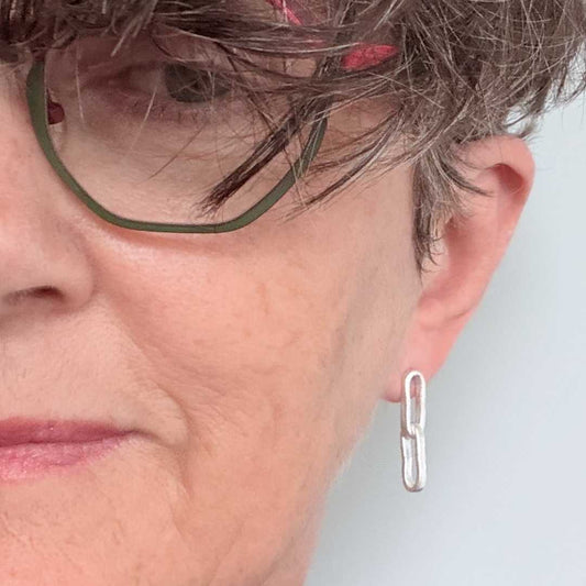Sally Herbert wearing Paperclip Chain Link Earrings in sterling silver, styled against a light blue background