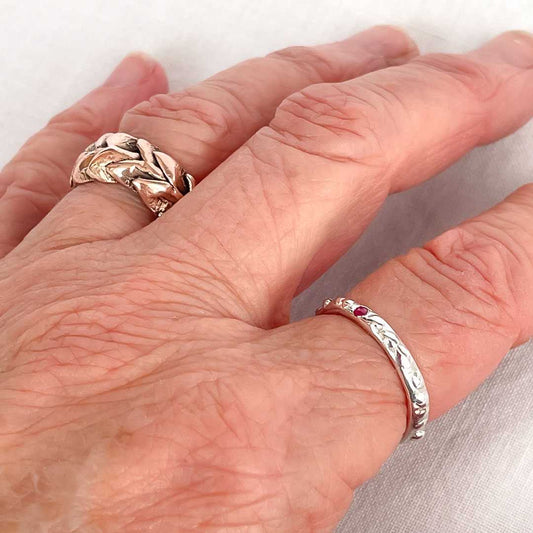 Fluid Ember Stacking Ring in sterling silver with a flush-set natural ruby, worn alone on the hand.