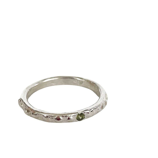 Fluid Nova Stacking Ring in sterling silver with a flush-set natural green sapphire, shown against a white background."
