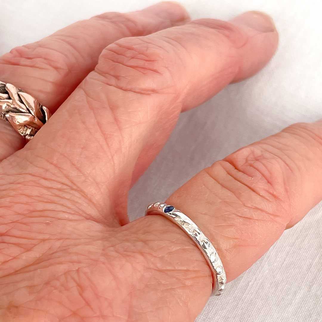 Fluid Nova Stacking Ring in sterling silver with a flush-set natural blue sapphire, worn on the hand