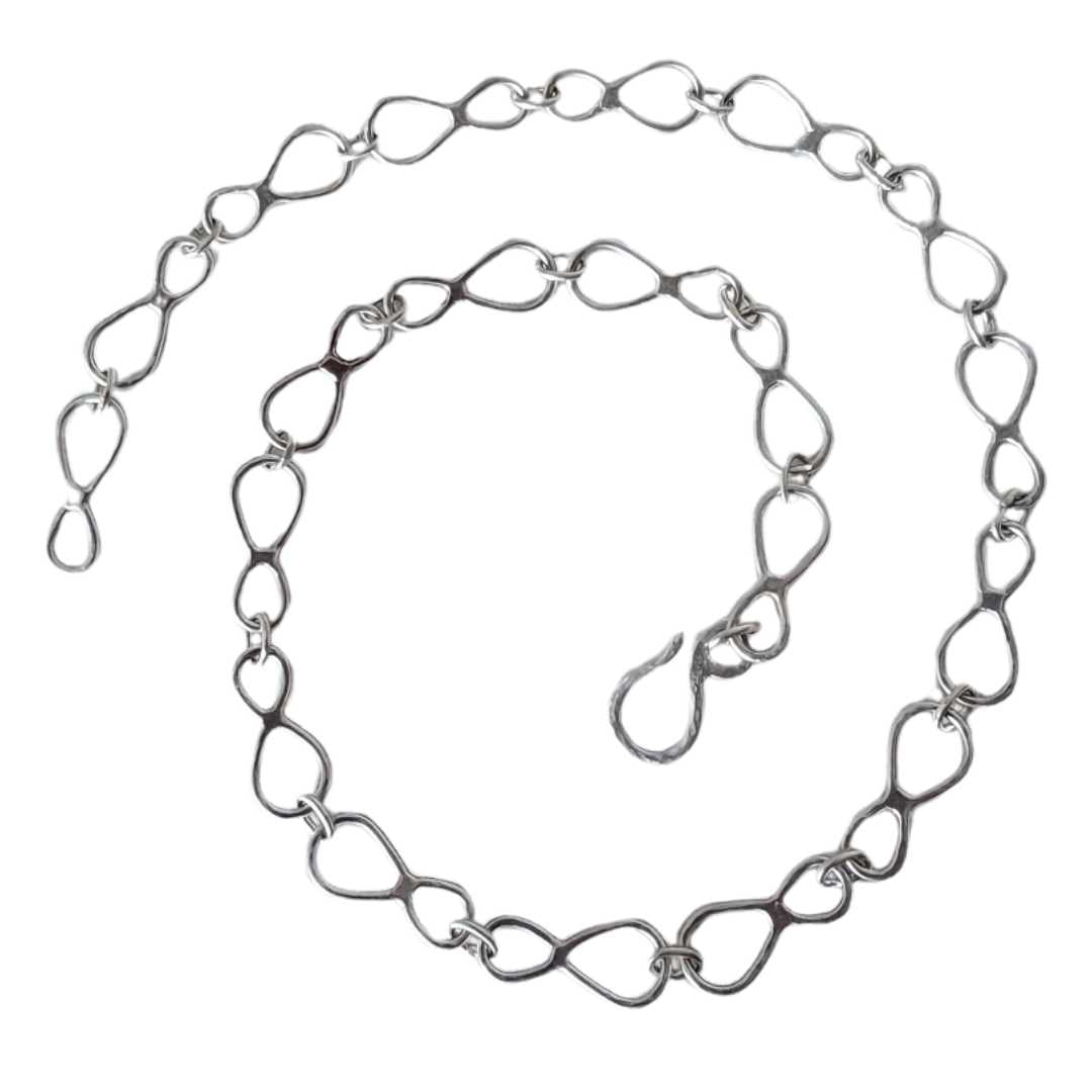 Still Loop sterling silver chain necklace coiled in a spiral on a white background.