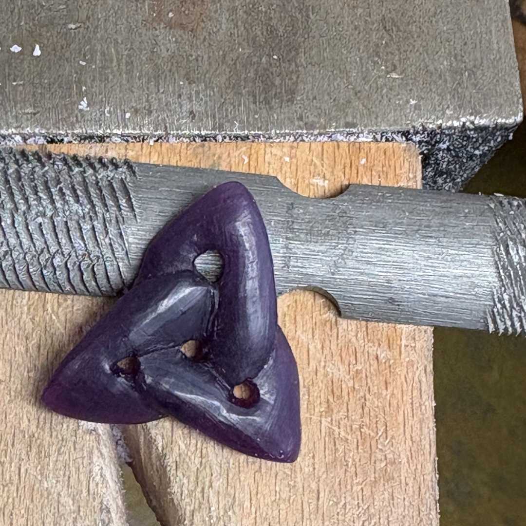 Close-up of an in-progress sculptural purple wax piece resting on a metal file at a jewellery making bench.