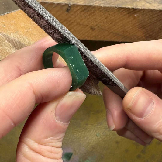 Filing a green wax ring prototype with a hand tool during a lost wax carving jewellery workshop in Auckland.