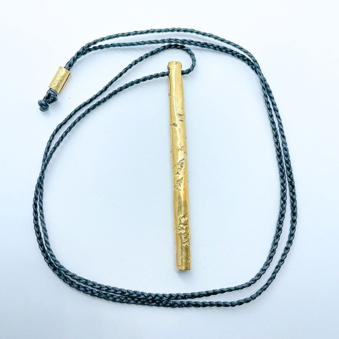 Wrapped pendant laid flat with the black cord looping around the pendant