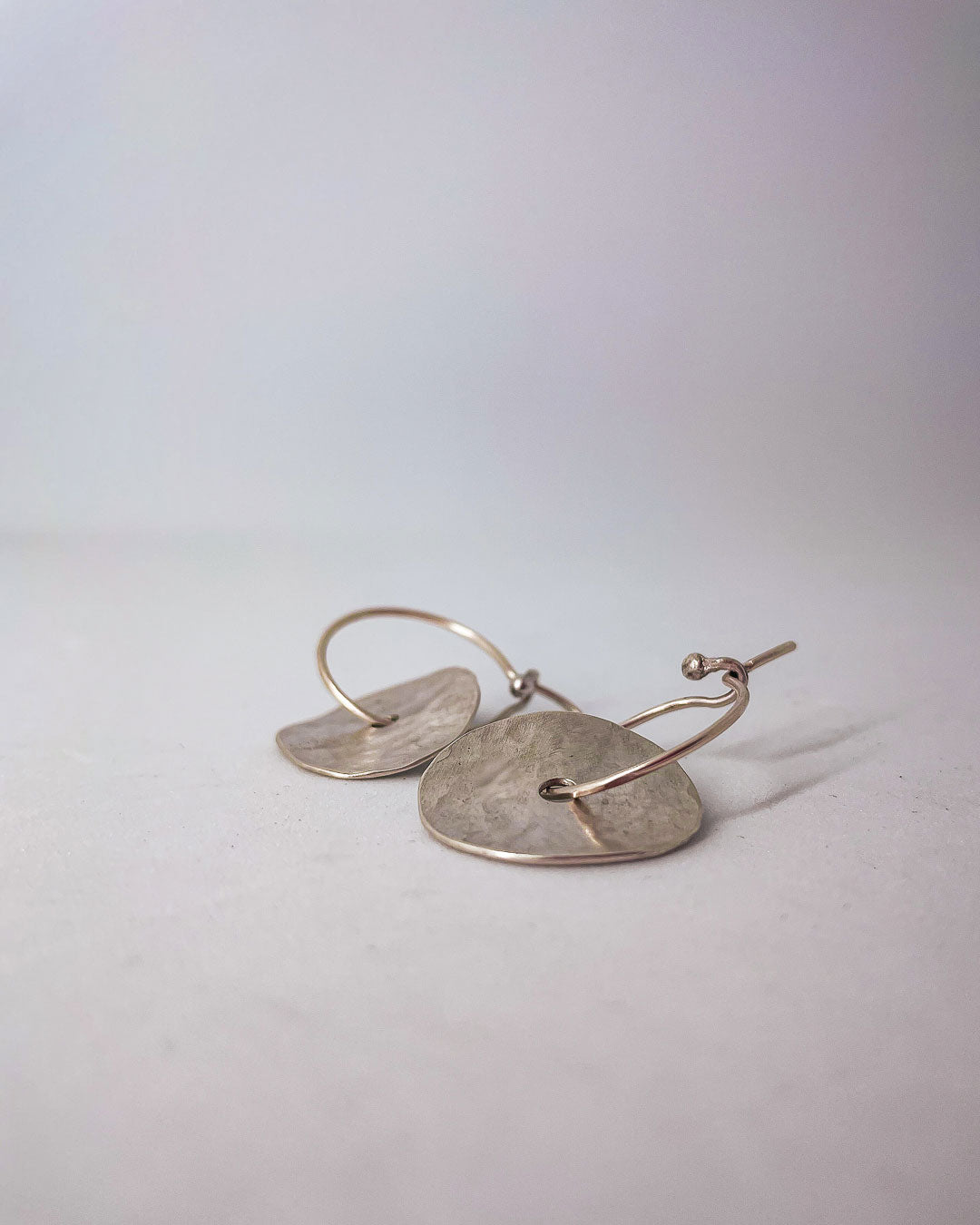 A pair of discs of Sterling Silver that sits on a hoop earring