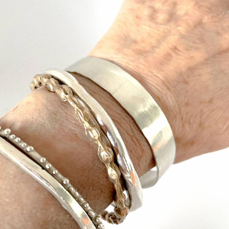 A collection of Bangles being worn including the Heavy Textured Unisex Bangle - standard width