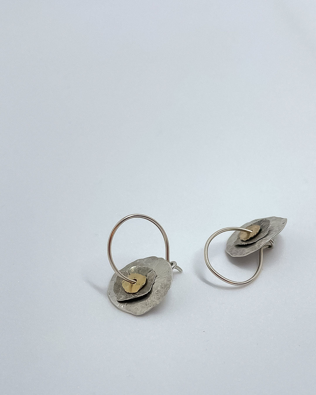 Multi layered Silver and 9ct Gold hand fabricated Hoop earrings lying on a surface