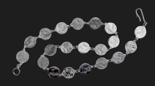 HerbertandWilks Jewellery sterling silver Sequin necklace on a dark charcoal background, displaying the various handcrafted textures on the discs.