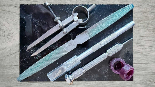 Wooden jewellery workbench with wax ring blanks, carving tools and wax dust from handmade ring making process