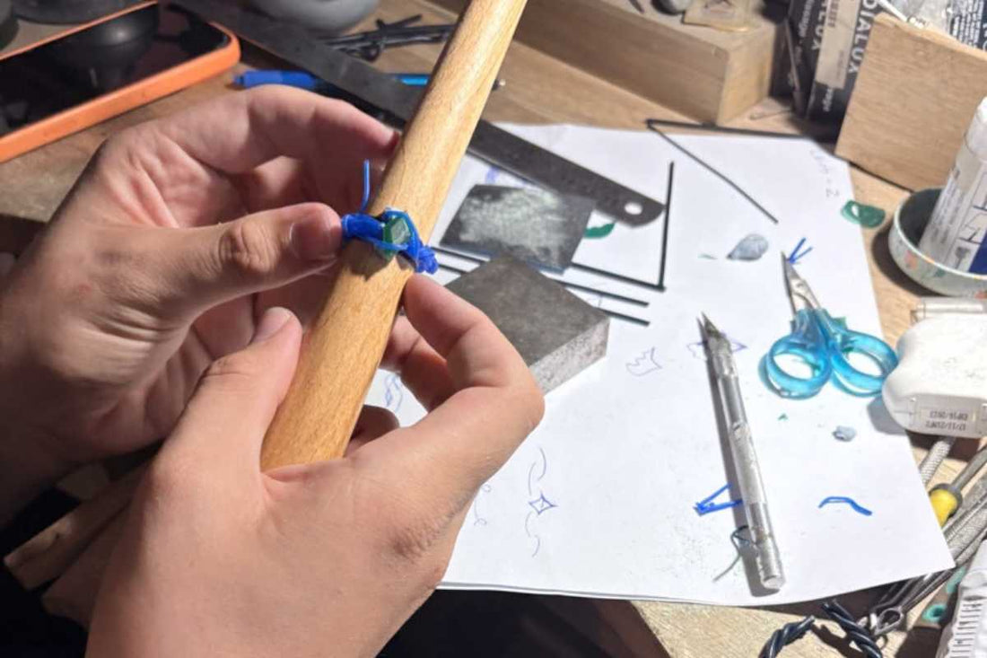 Hands shaping silver ring on jeweller's bench with tools and design sketches at HerbertandWilks workshop Mt Eden Auckland