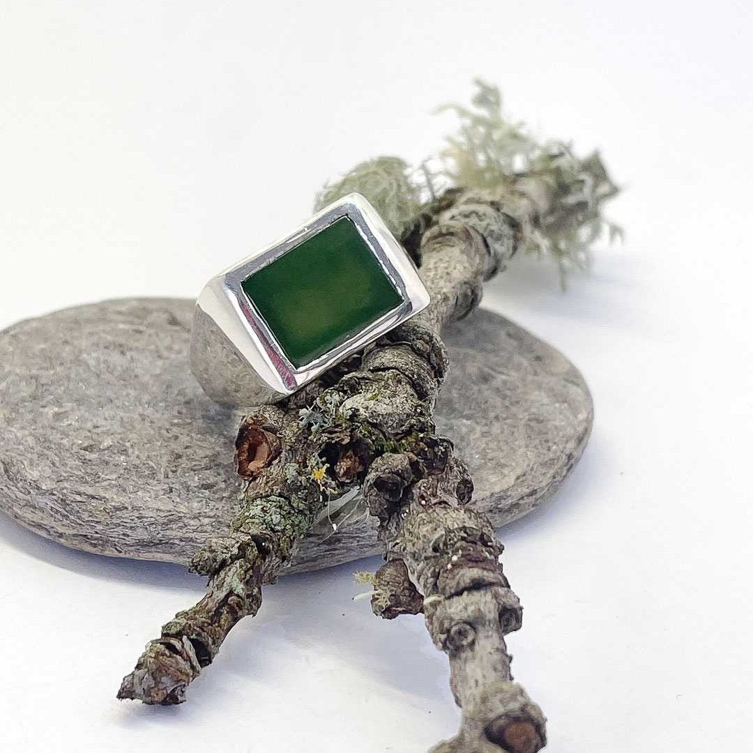 Horoeka Signet Ring resting on a smooth stone and leaning against a textured branch, showing the handcrafted silver detail and organic form.