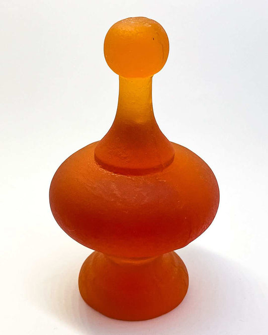 A Orange Cast Glass Finial  lit to showcase its intricate curves and varying depths, highlighting the glass's colour tones and translucency.
