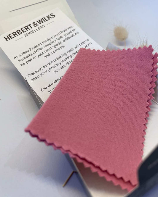An Image of what is inside the ring poliishing cloth kit - A 9cm x 12cm impregnated easy-to-use jewellery polishing cloth that renews the sparkle on silver, gold, platinum, diamonds, sapphires, rubies and  a information card