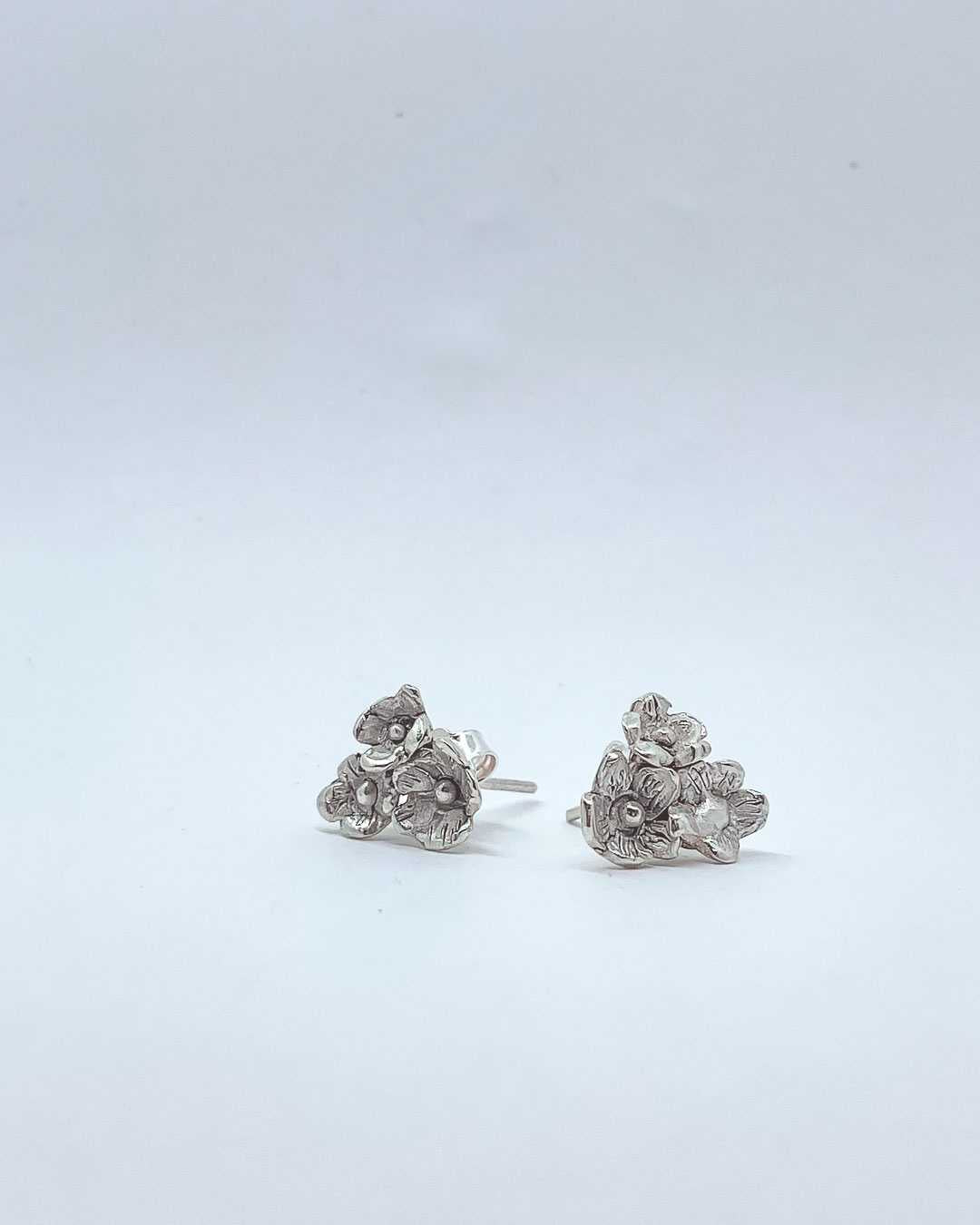 A side profile and front view of a pair of Sterling Silver Flower bouquet Stud Earrings made of 3 Flowers each earring.