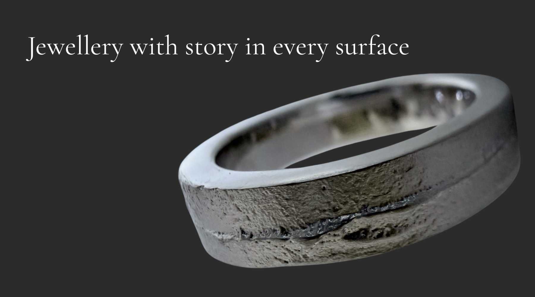White gold sandcast ring on a charcoal background with the words “Jewellery with story in every surface”, showing its textured handmade surface