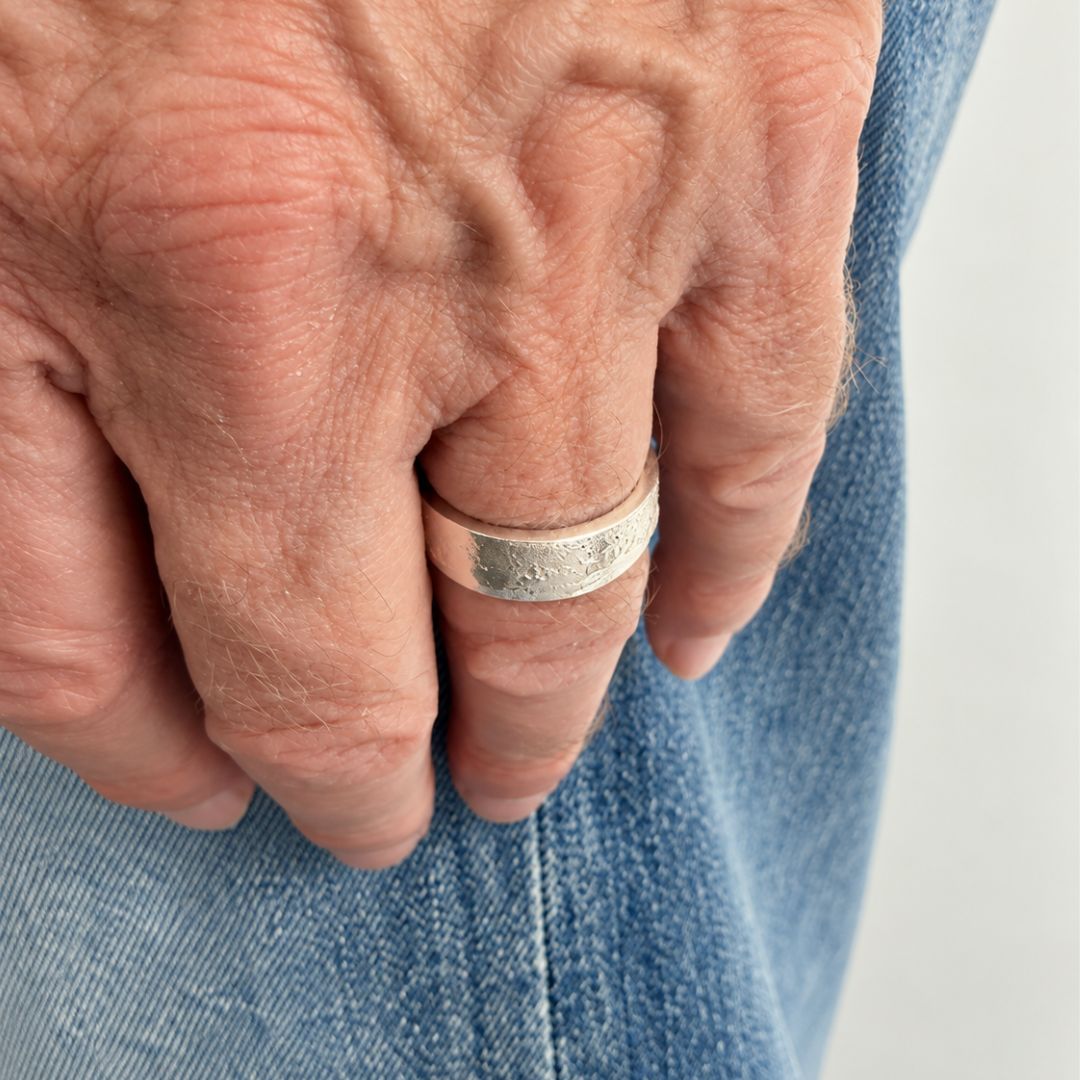 7mm sterling silver sandcast ring worn on the hand against blue denim