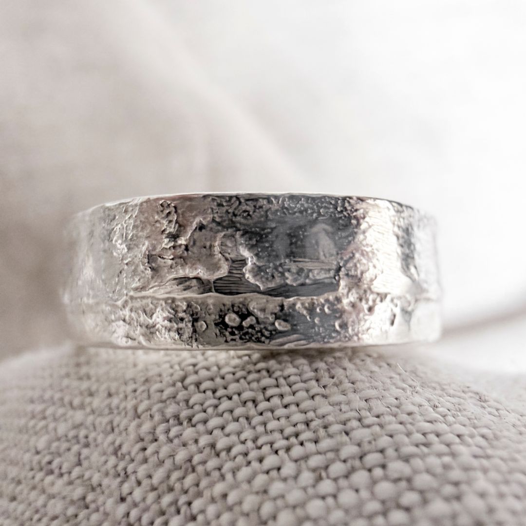 Close-up detail of sterling silver sandcast ring showing irregular texture and casting marks