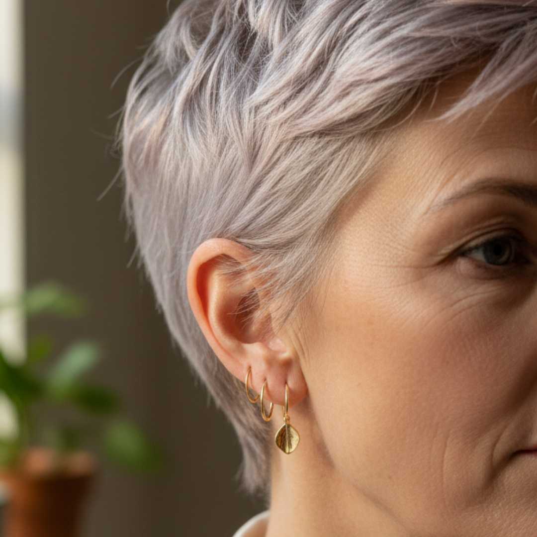 Woman 60s wearing stacked 12mm gold sleeper earrings with charm - ageless style