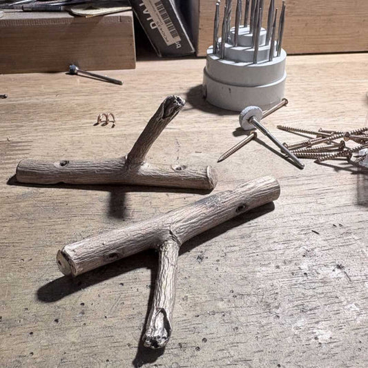 Two bronze apple tree hooks in workshop showing handcrafted casting process before final finishing