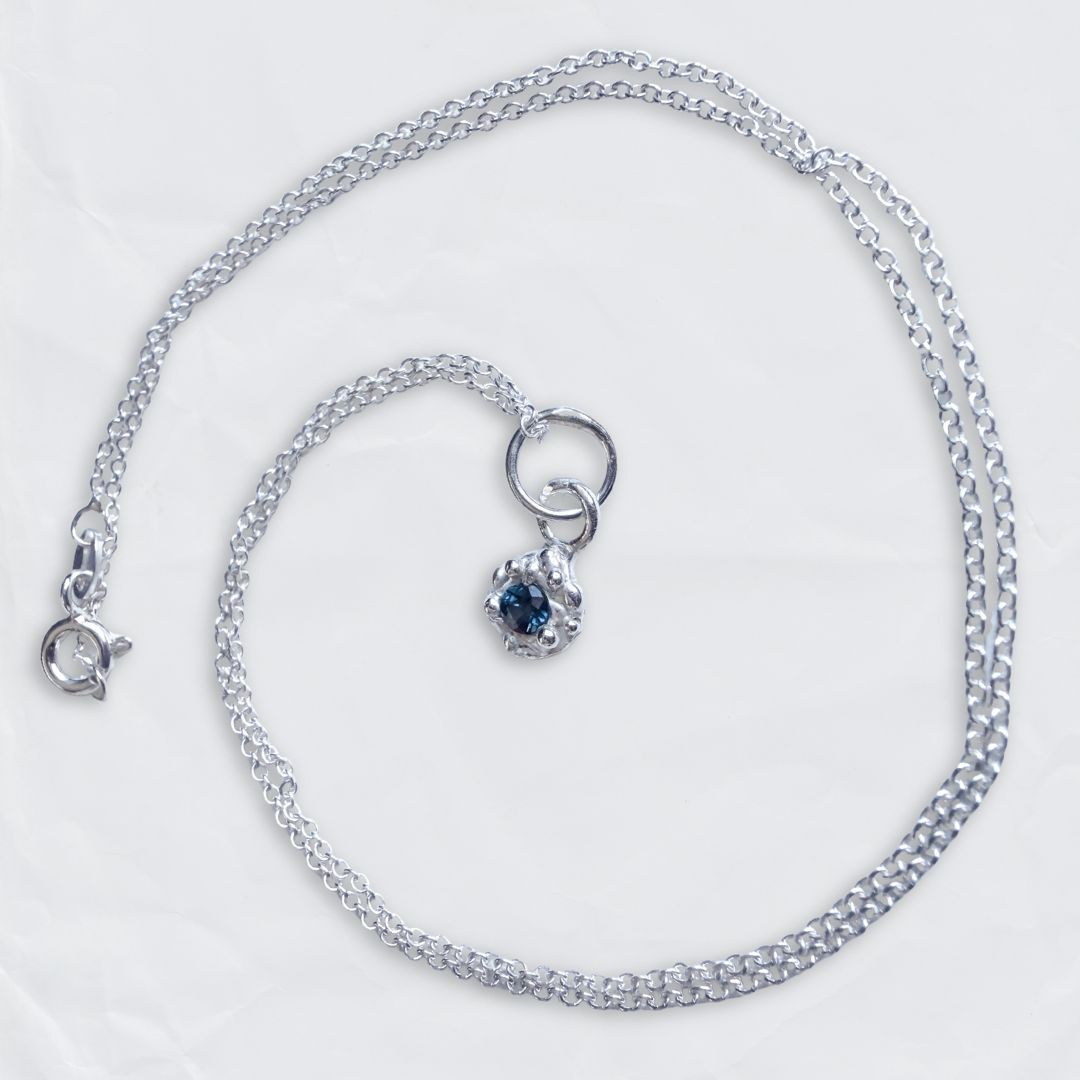 Fine sterling silver Dewdrop pendant featuring a natural blue sapphire gemstone, displayed on a clean background.