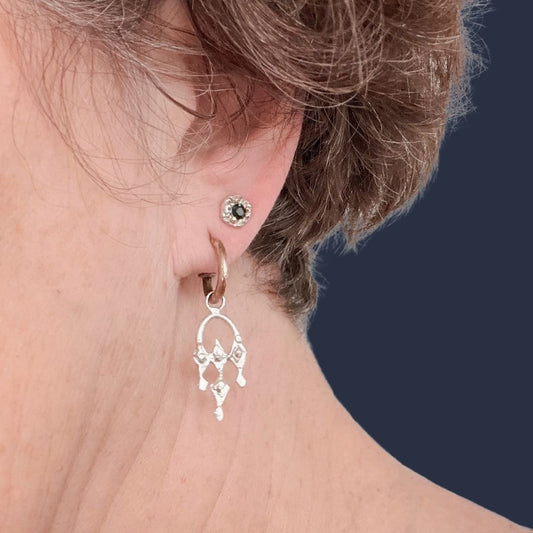 Sterling silver Dewdrop Sapphire Stud Earring worn on the ear, featuring a small organic textured setting and deep blue sapphire.