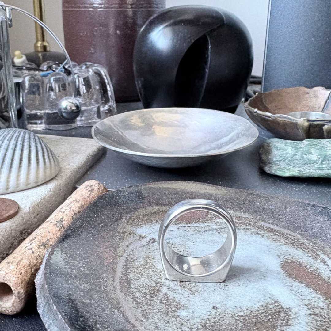 Eden Signet Ring resting face-down in handmade pottery bowl, styled with curated ceramic objects and ornaments