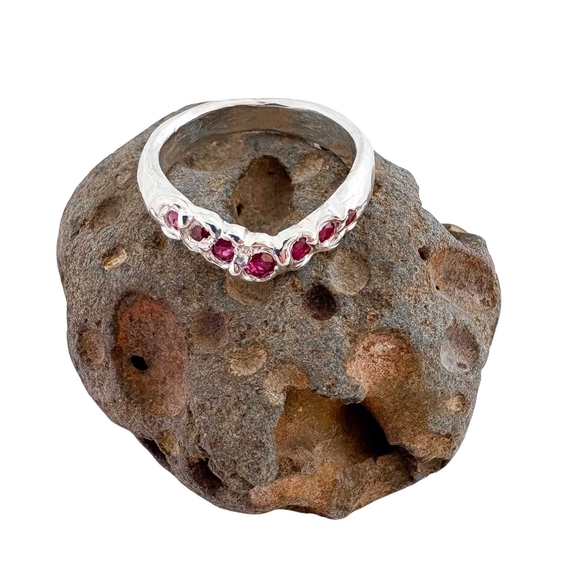 The Arc Ruby Ring sitting on a textured and sculptural rock against a white background