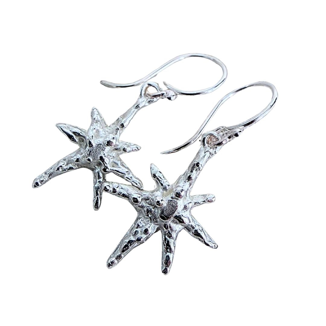 Faerie Star dangle earrings in sterling silver with organic textured star forms and handmade ear hooks on a white background.