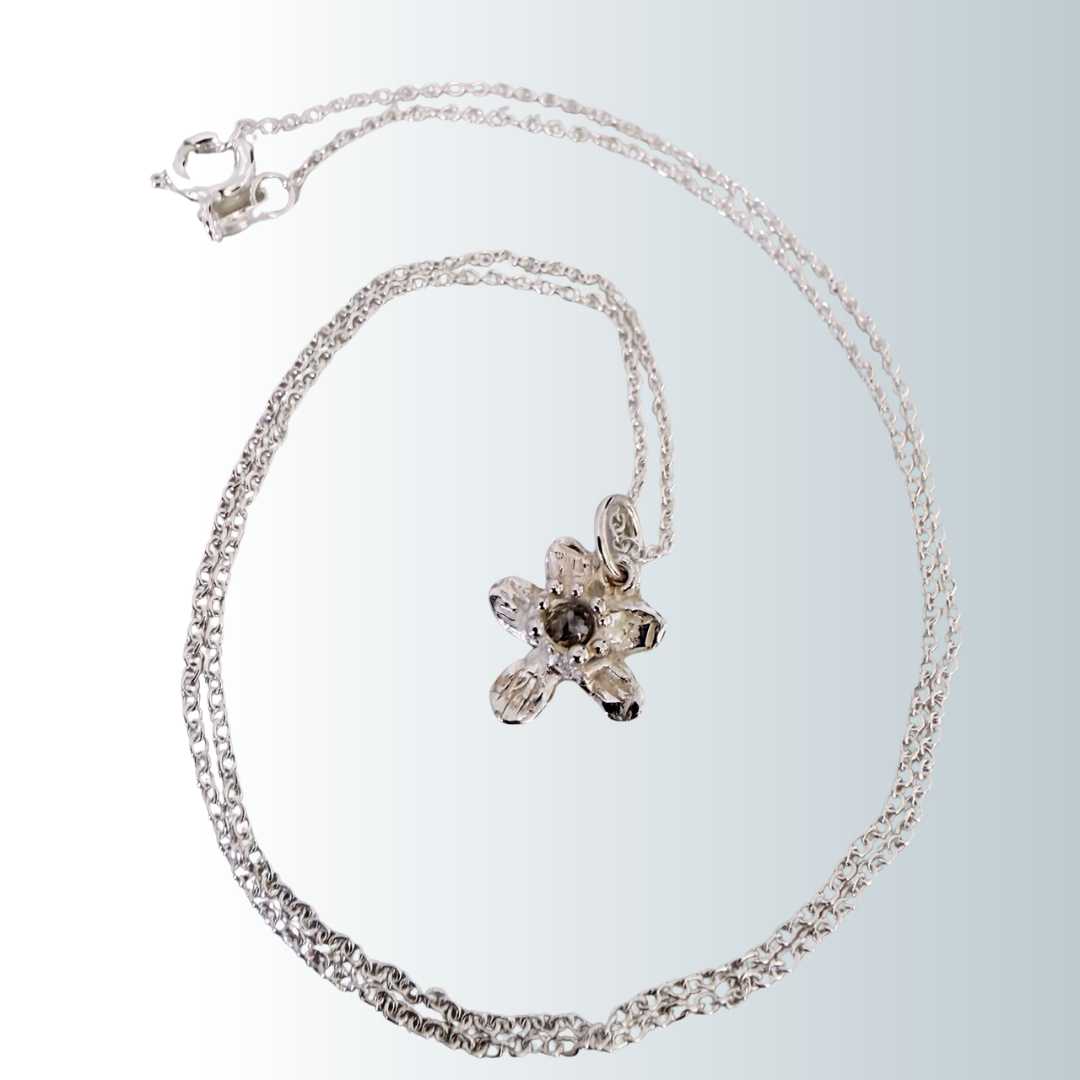 Flora Diamond Pendant Necklace variation - sterling silver flower pendant with unique salt and pepper diamond, chain spiraling around pendant