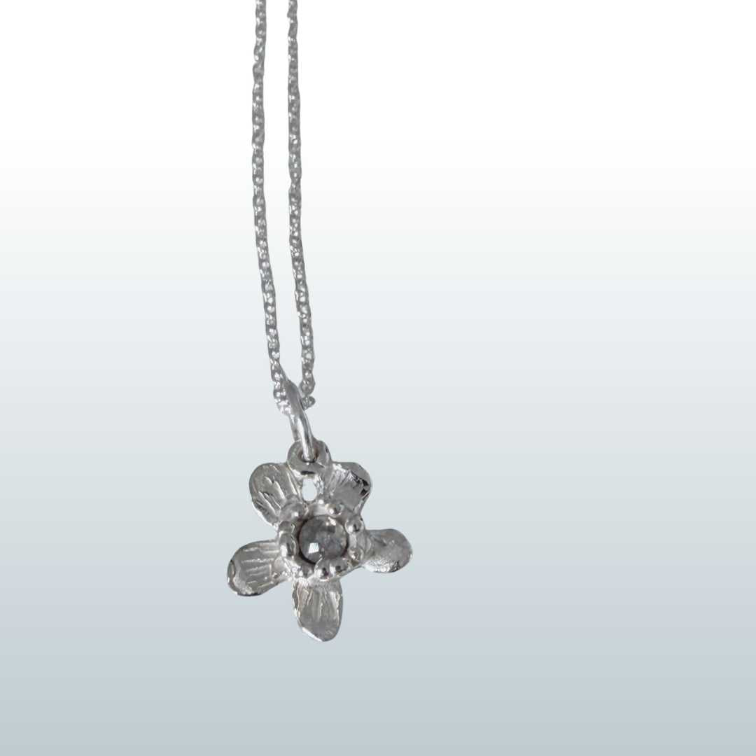 Flora Diamond Pendant Necklace detail - sterling silver flower pendant with rose-cut salt and pepper diamond, chain flowing upward