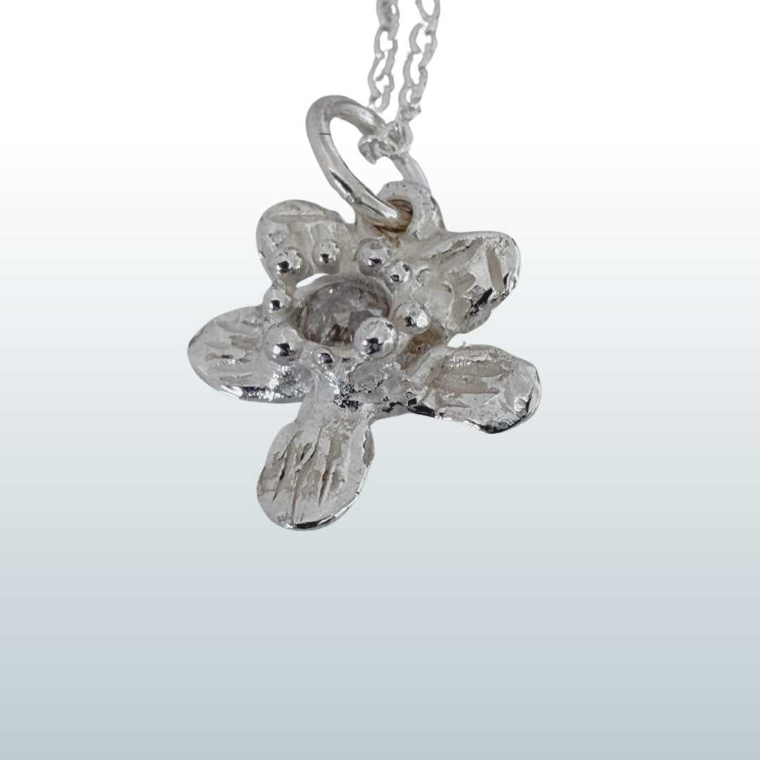 Close-up of Flora Diamond Pendant showing three-dimensional sculptural detail of sterling silver flower and rose-cut salt and pepper diamond