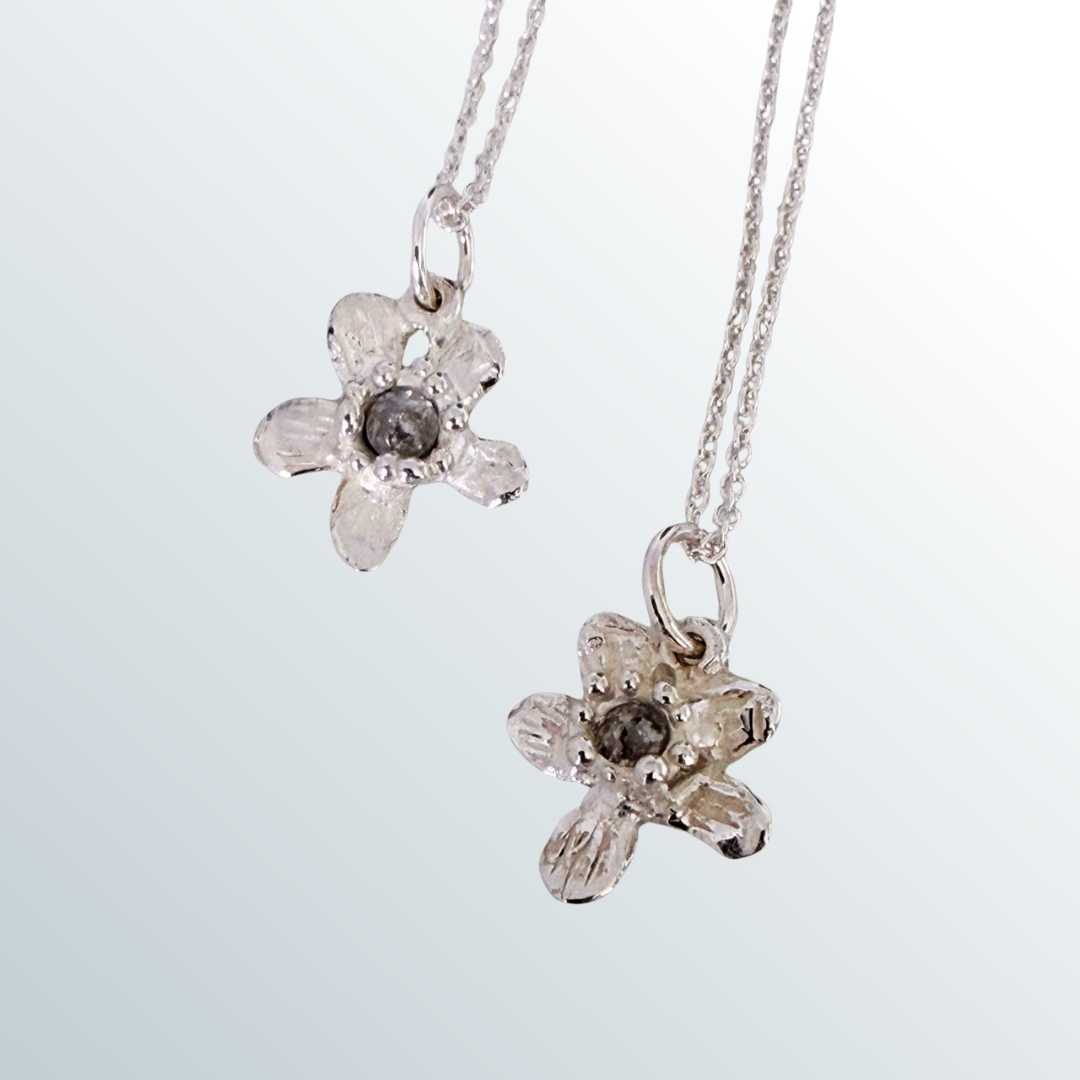 Two flowers comparison: "Two Flora Diamond Pendants showing natural variations in hand-built sterling silver flowers and salt and pepper diamonds